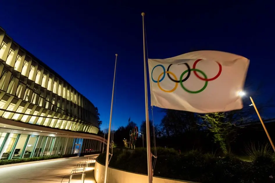 The Olympic flag is displayed at the entrance of the IOC headquarters in Lausanne, Switzerland, March 23, 2020. © 2020 Jean-Christophe Bott/Keystone via AP