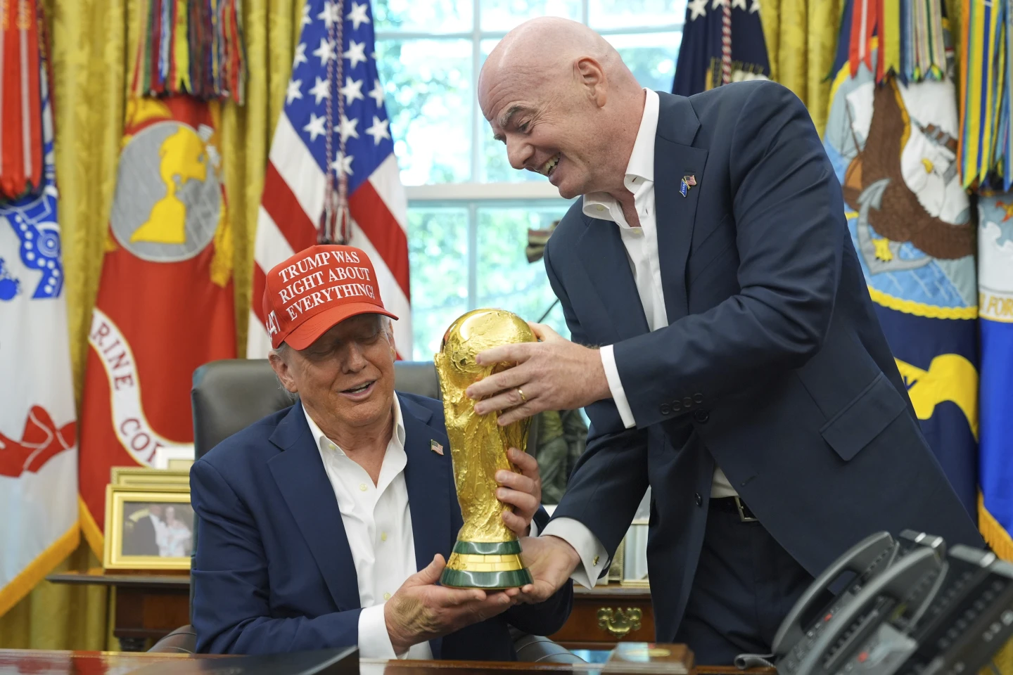 FIFA President Gianni Infantino, right, hands the FIFA World Cup Winners Trophy to President Donald Trump during an announcement in the Oval Office of the White House, Friday, Aug. 22, 2025, in Washington.